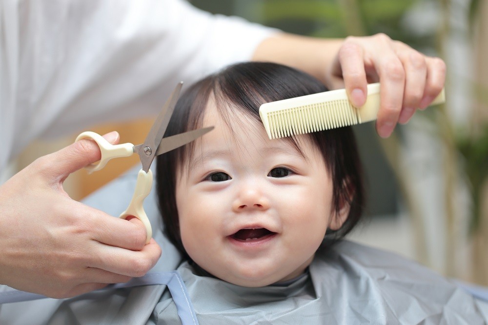 ケープをつけて前髪をカットされている子ども