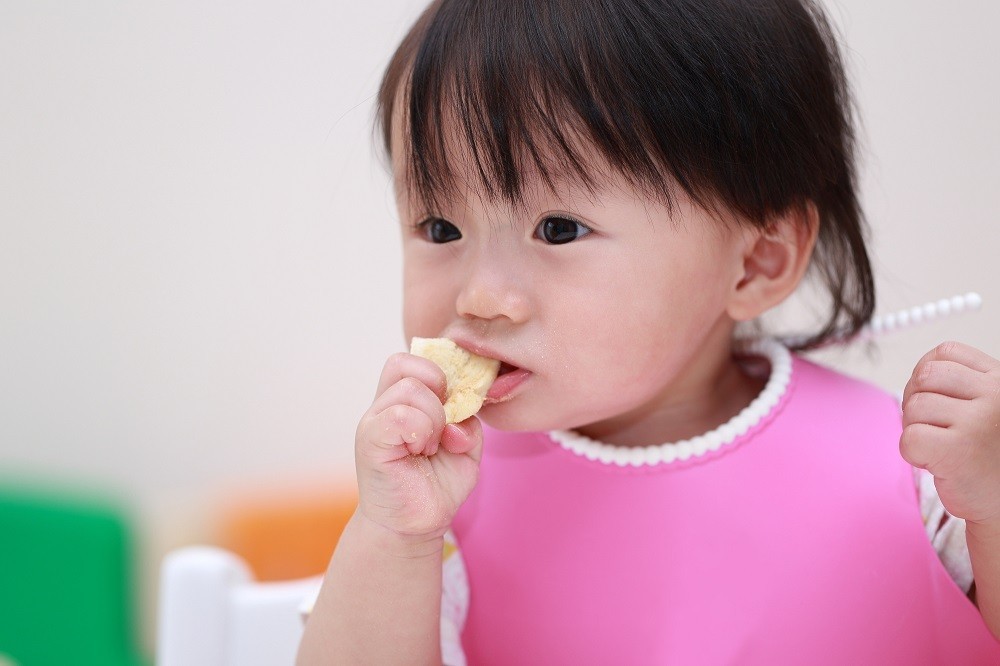パンを手に持って食べている子ども