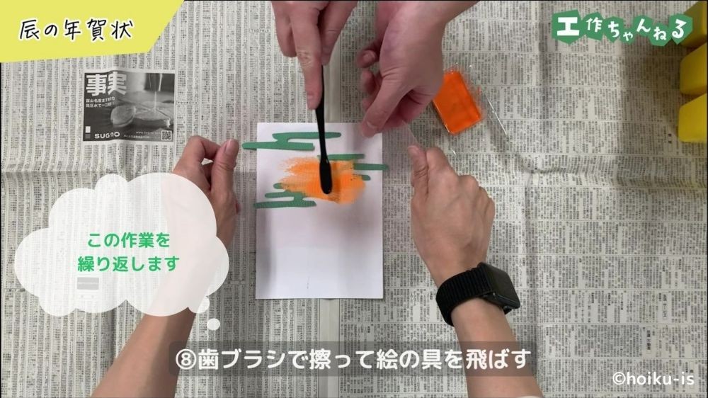 網にのせた絵の具を歯ブラシで画用紙に飛ばしている手元