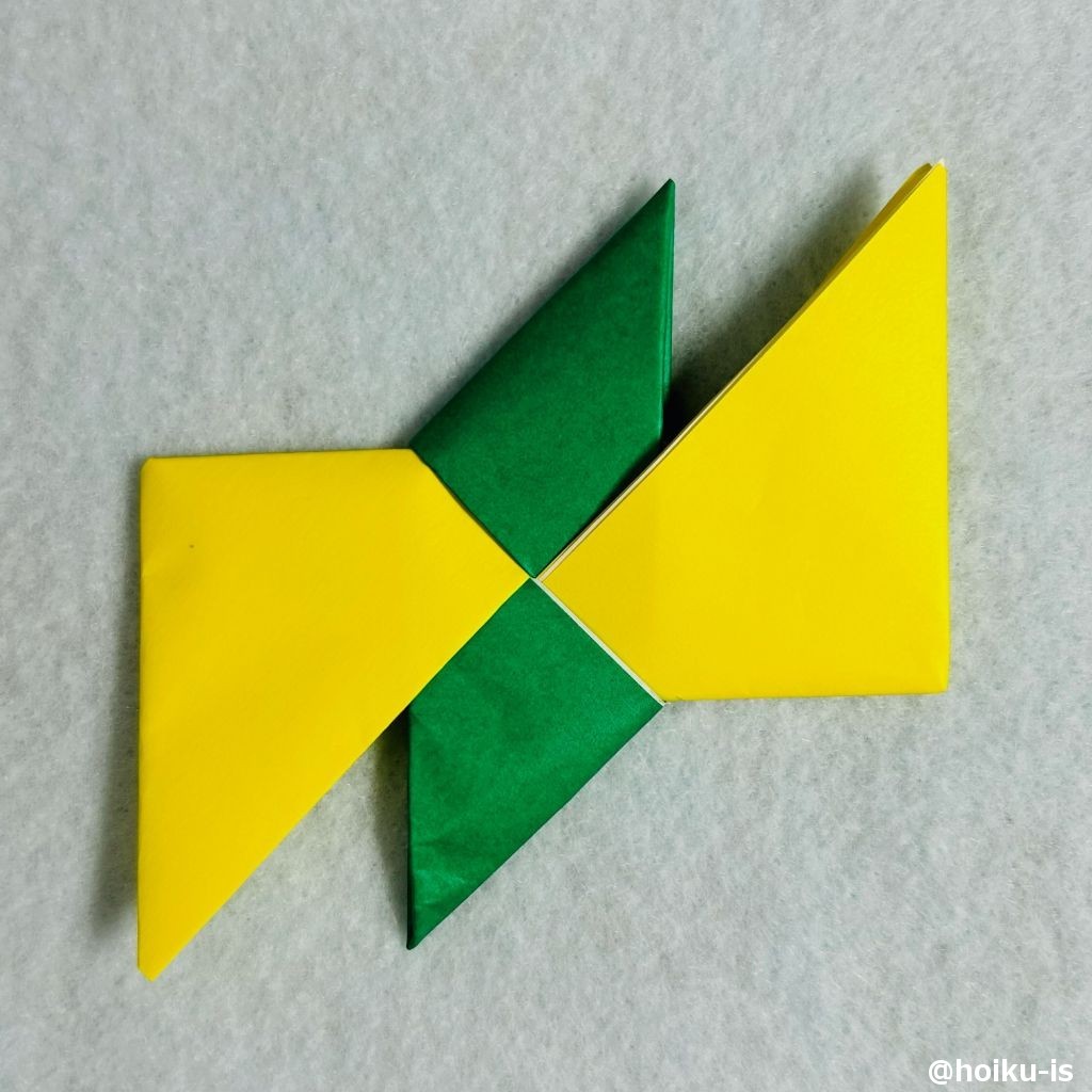 ⑭同じように下の三角形も中心に向かって折り、黄色の折り紙に差し込む。