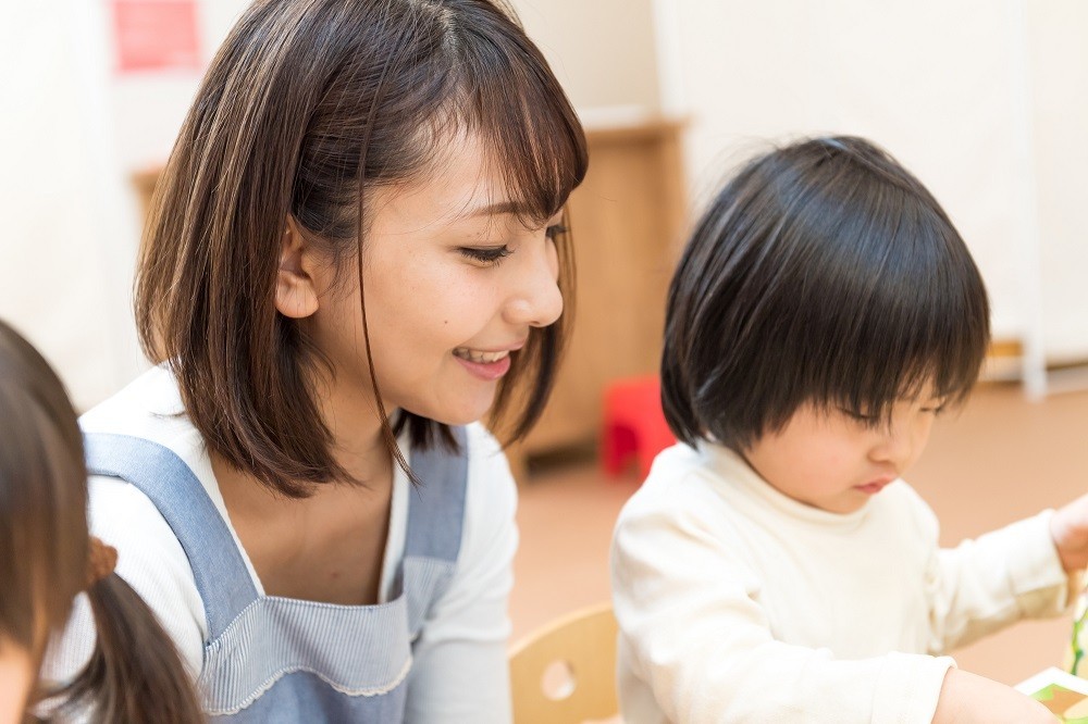 子どもの遊びを見守る保育士