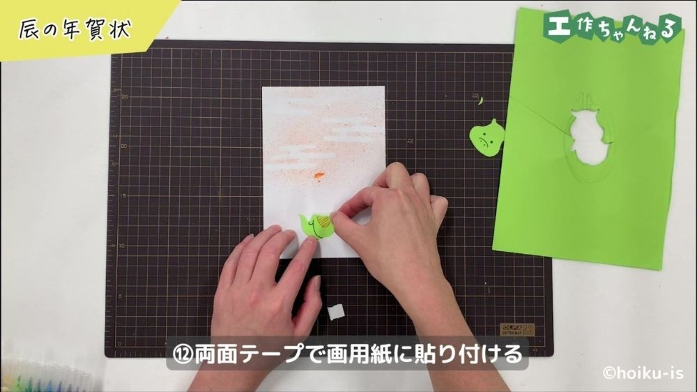 画用紙に辰のパーツを貼り付けている手元
