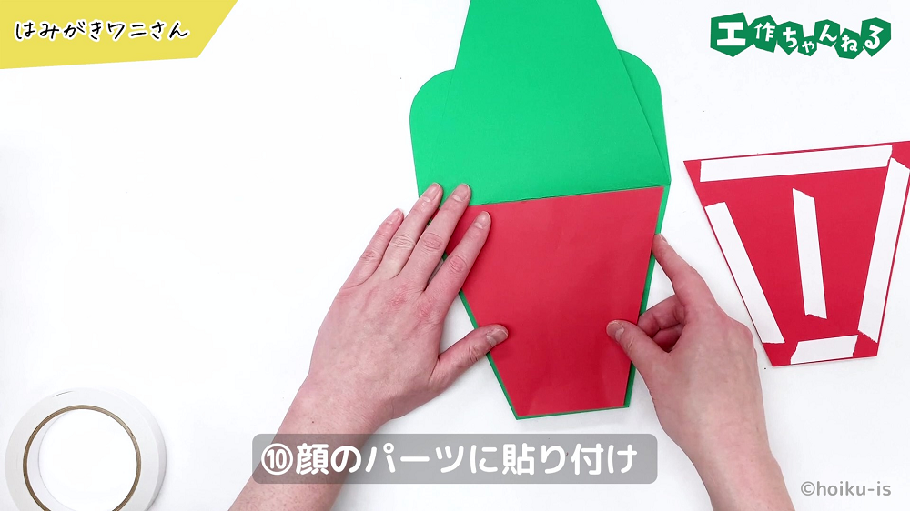 緑の画用紙に赤い画用紙を貼り付けている手元