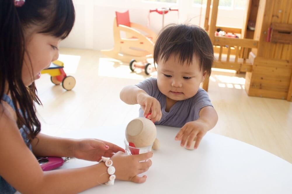 おもちゃで遊ぶ女の子とあかちゃん