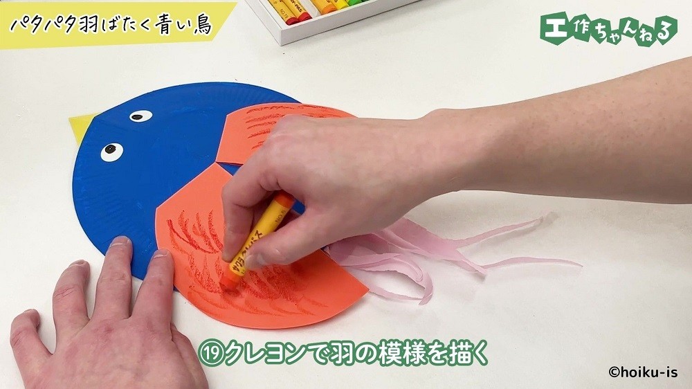 オレンジのクレヨンで色を塗っている手元