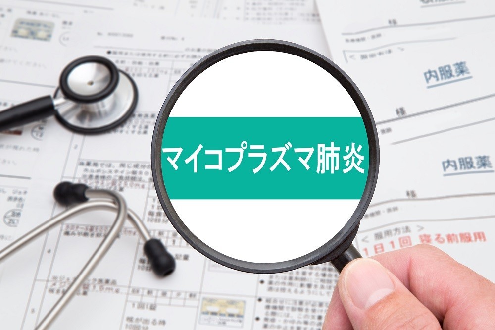 虫眼鏡で拡大された「マイコプラズマ肺炎」の文字