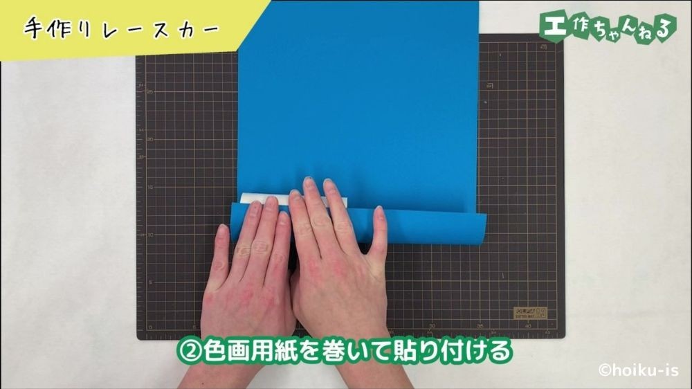 トイレットペーパーの芯に画用紙を貼り付けている手元