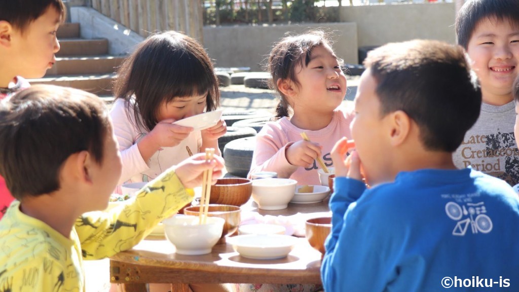 外で食事をする保育園の子どもたち