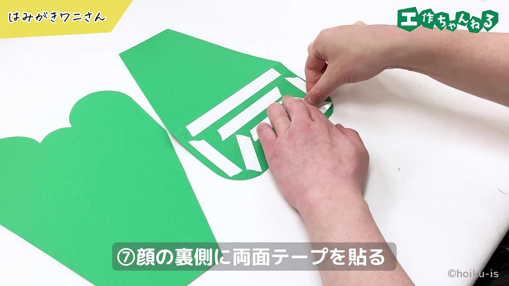 画用紙に両面テープを貼り付けている手元