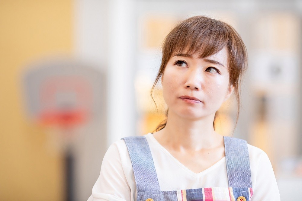 斜め上を見て考えごとをしている保育士