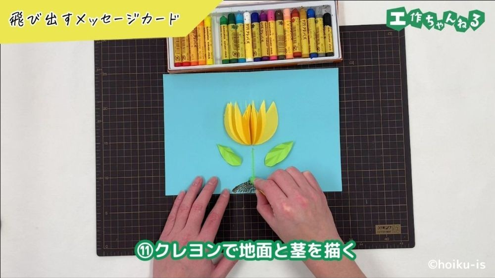 クレヨンでカードの絵を描いている手元