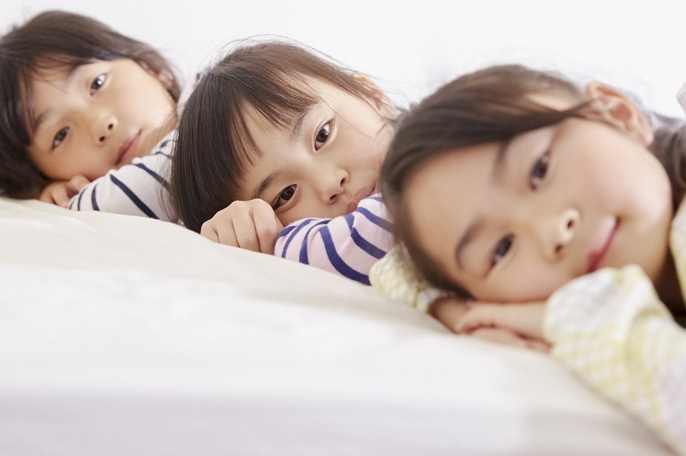 ベッドに寝そべっている3人の子ども