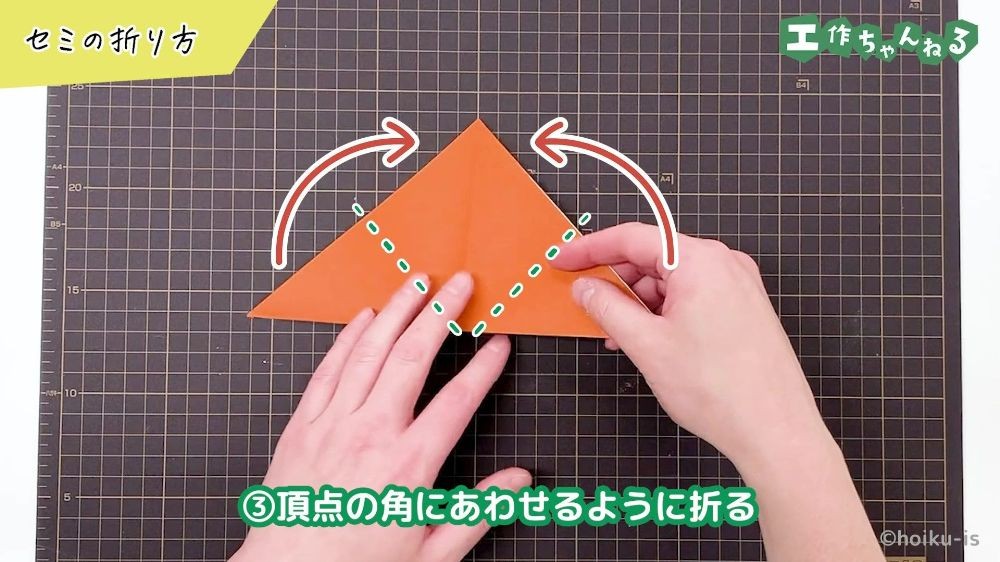 三角に折った折り紙の角をあわせるように折っている様子