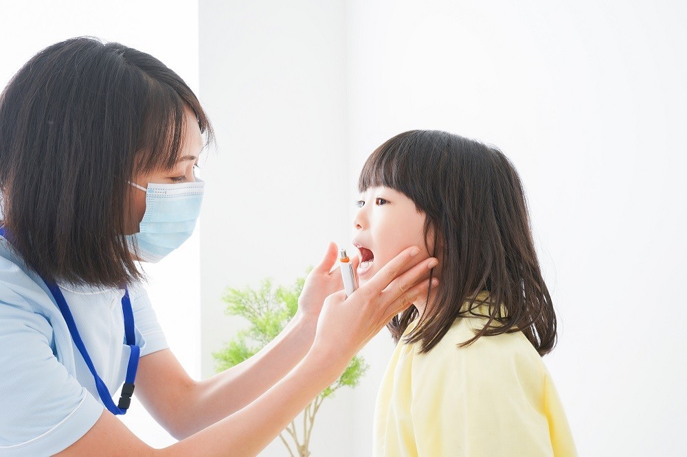 女の子の体調を確認する保育園看護師