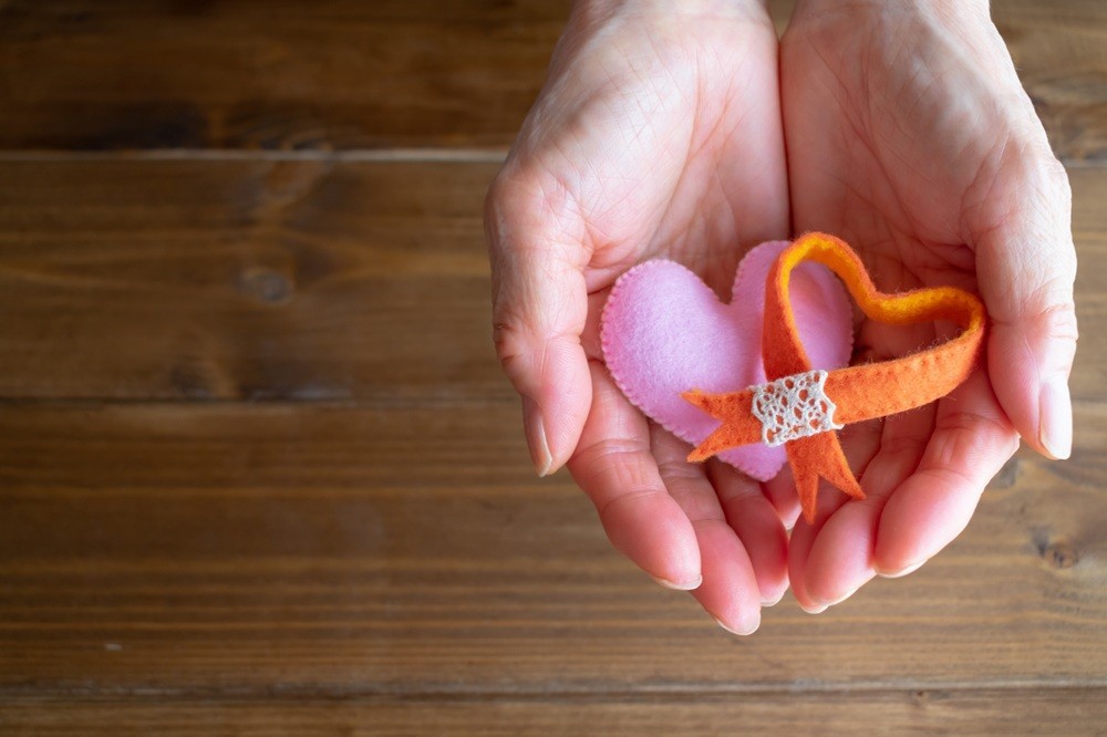 手のひらの上に乗ったオレンジリボンとハート