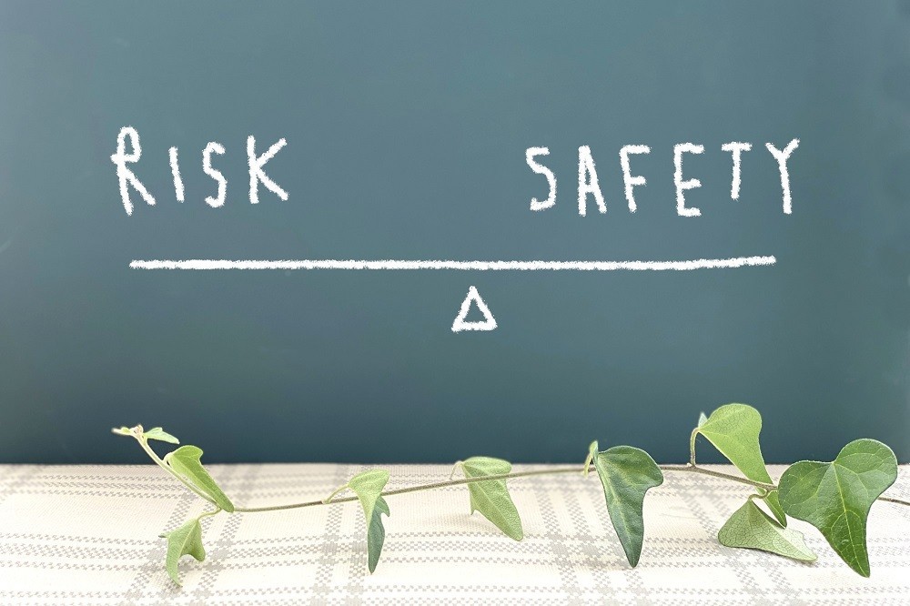 「RISK」と「SAFETY」の文字がシーソーに乗ったイメージ