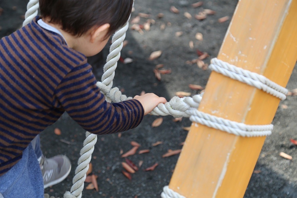 屋外の遊具で遊んでいる子ども