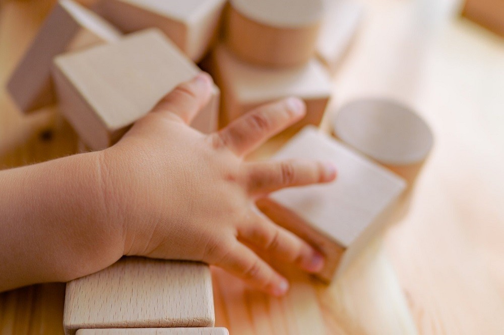 積み木のおもちゃに触っている子どもの手
