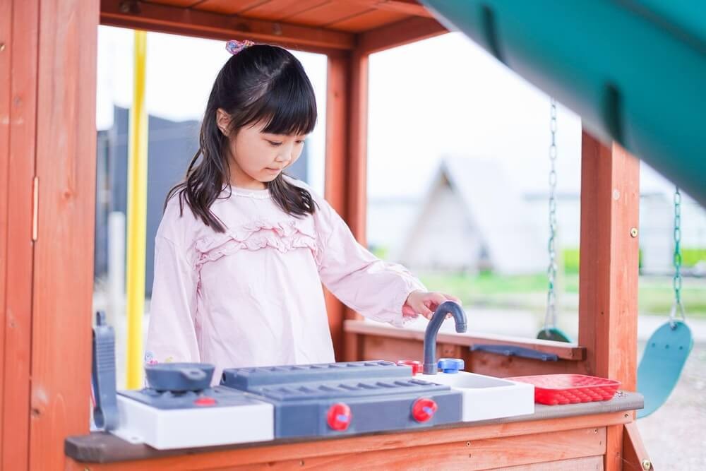 キッチン型のおもちゃで遊ぶ女の子