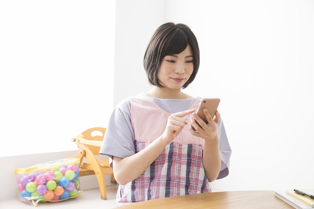 携帯を操作する保育士