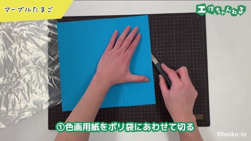 カッターで画用紙を切っている手元