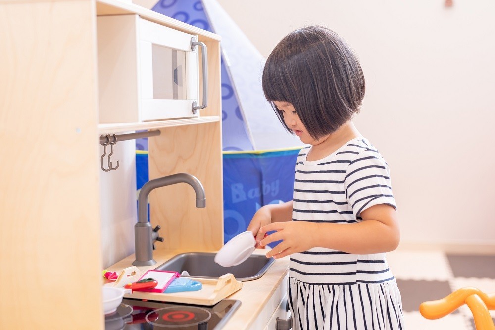 キッチンの遊具でままごと遊びをしている女の子