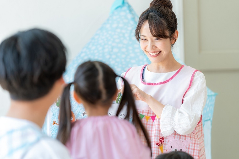 子どもたちの前で絵本の読み聞かせをする保育士