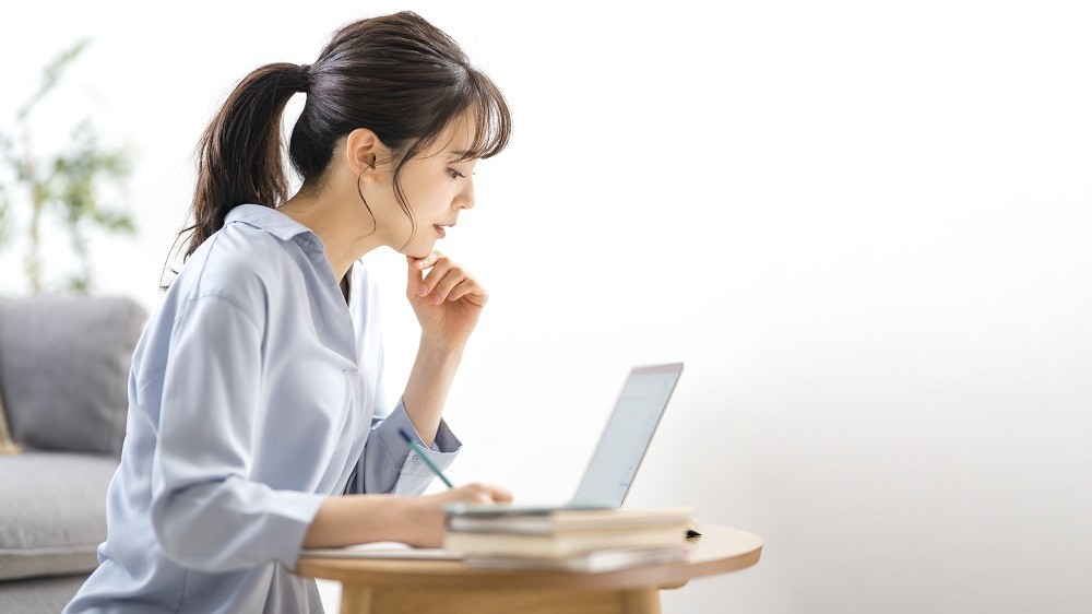 メモを取りながらパソコンを見ている女性