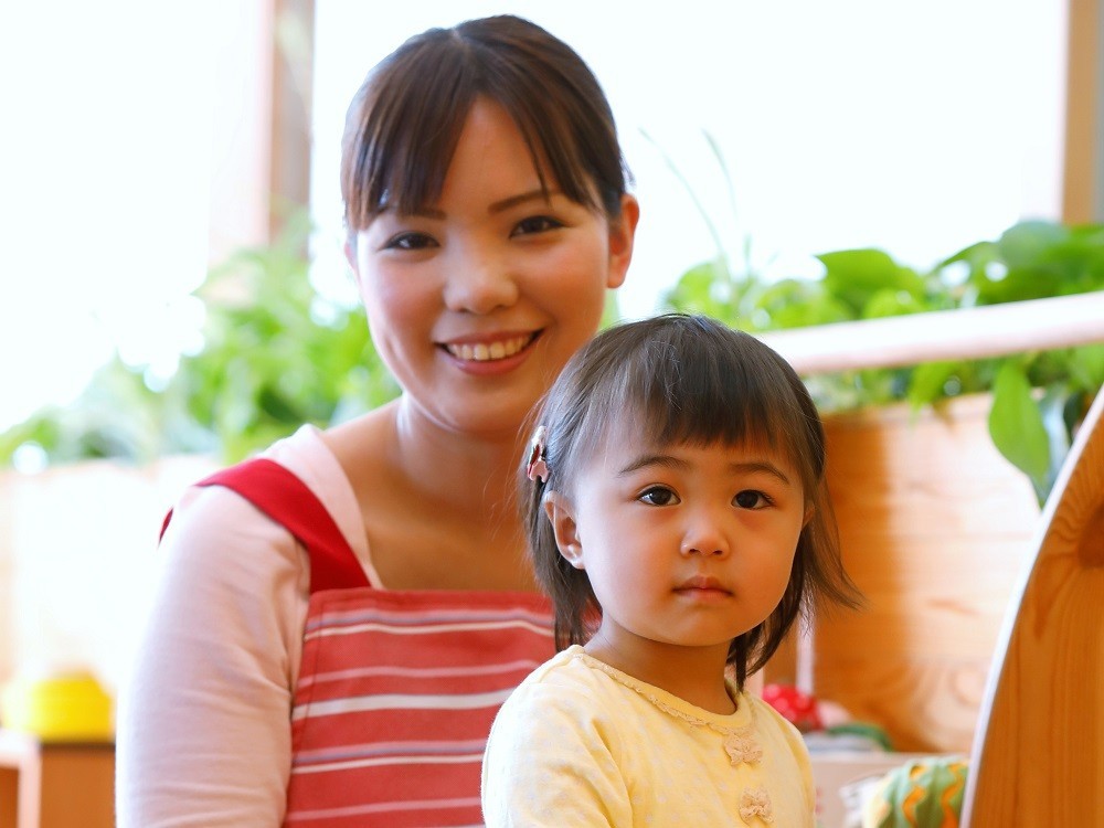 保育士と保育士の膝の上に座っている子ども