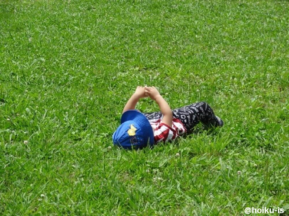 草原に寝転ぶ子どもの写真