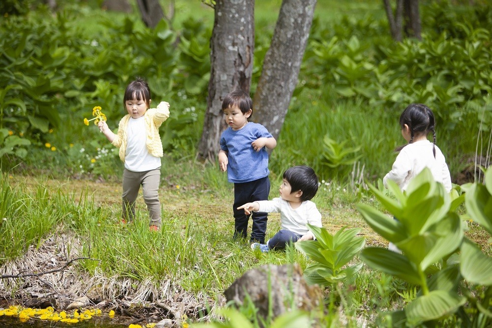 水に浮かぶ花を指さしている男の子とそれを見る子どもたち