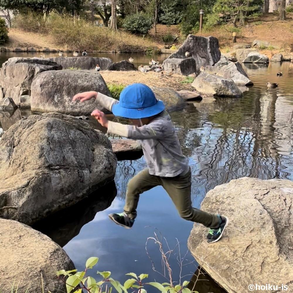 岩を岩を飛び越える子ども