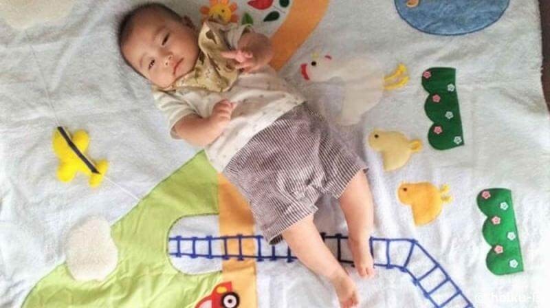 布おもちゃのマットに寝そべる赤ちゃん