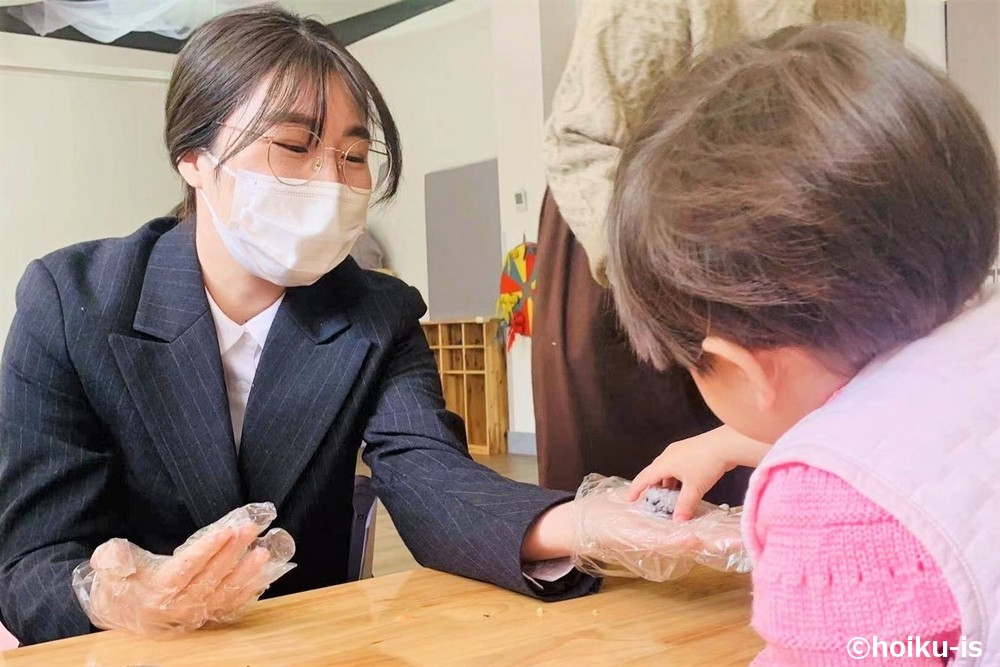スーツを着た女性が子供にご飯をあげている場面