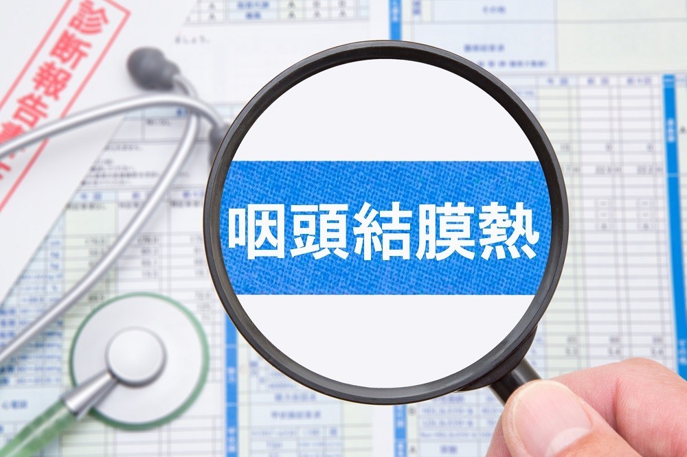虫眼鏡で拡大された「咽頭結膜熱（プール熱）」の文字