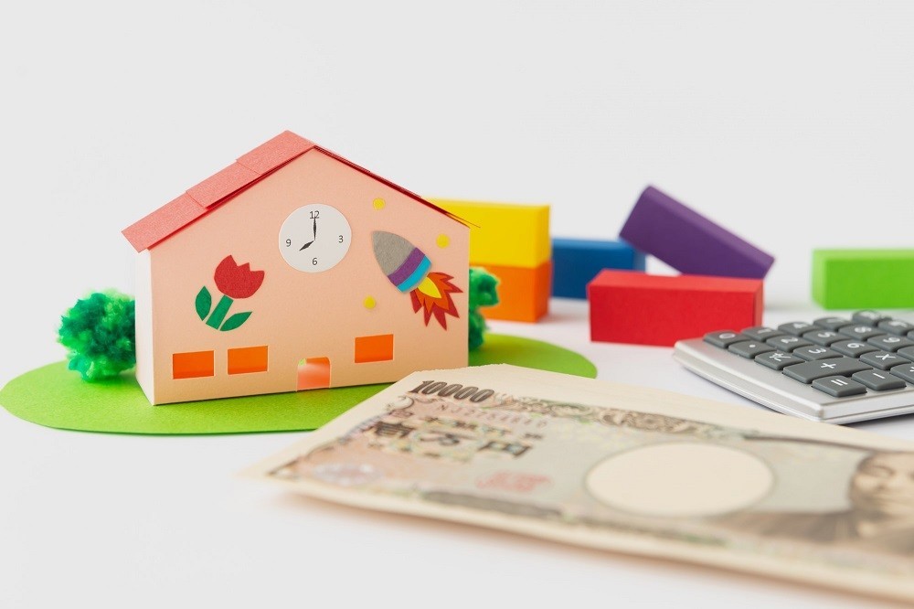 保育園の建物のミニチュアと電卓、お金