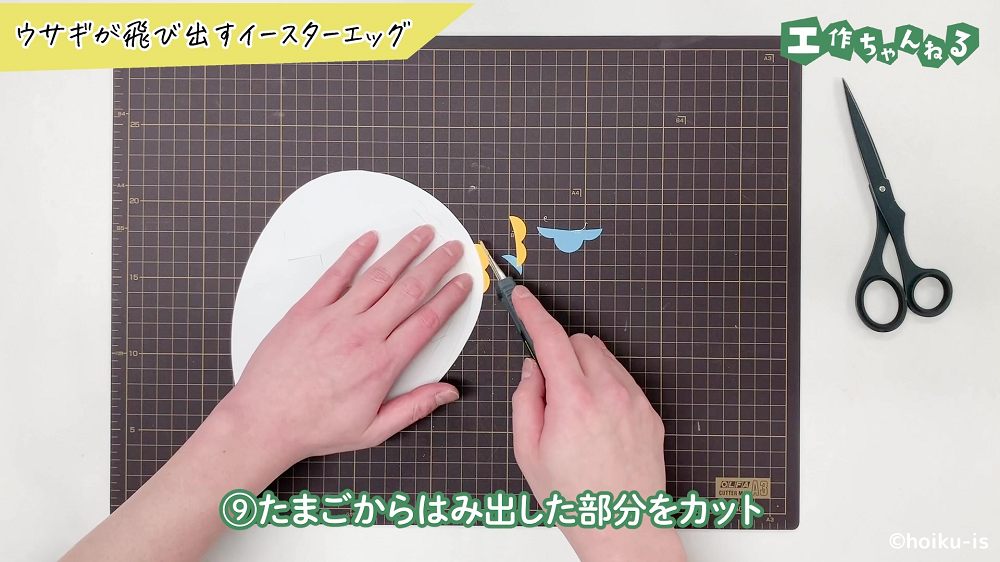 たまごからはみ出した部分画用紙をカットしている手元