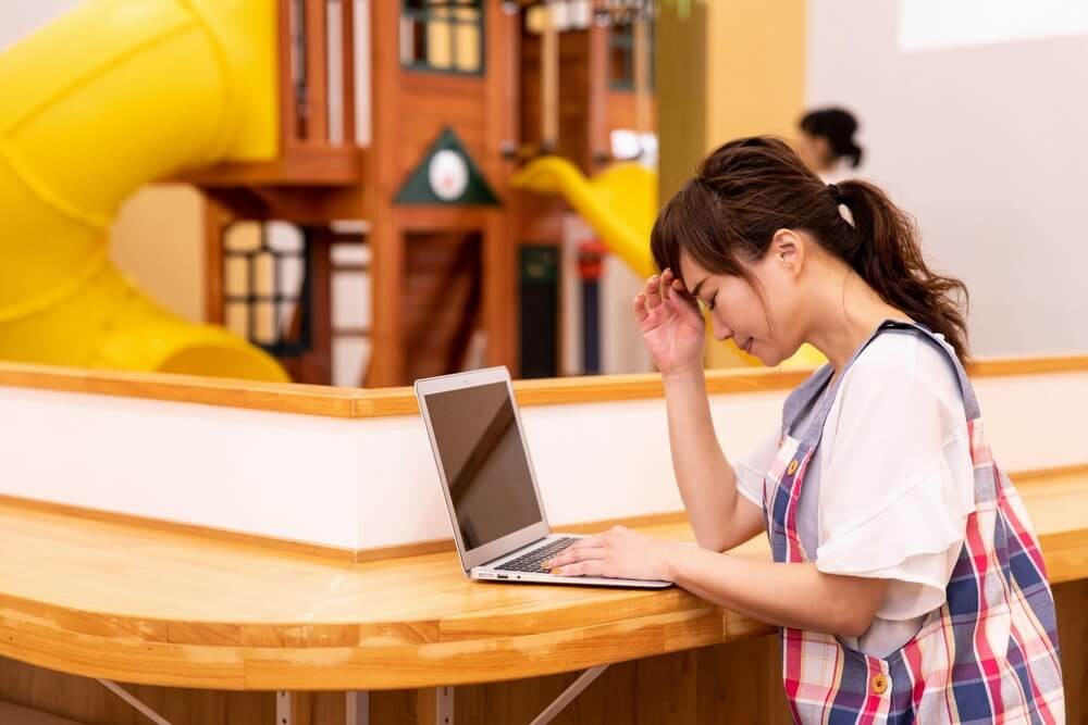 ノートパソコンの前で悩んでいる保育士