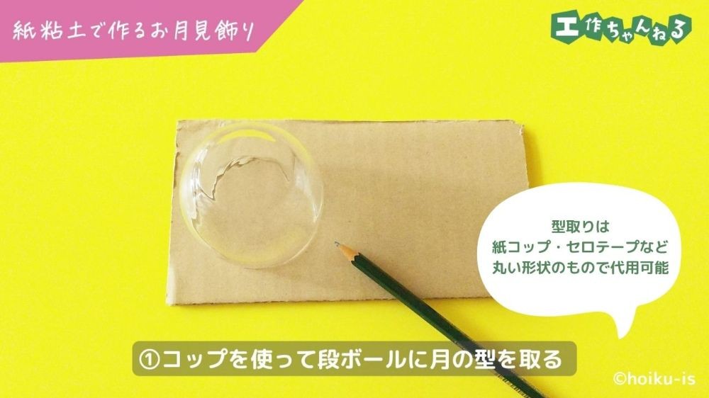 段ボールに丸いコップで型を取っている手元