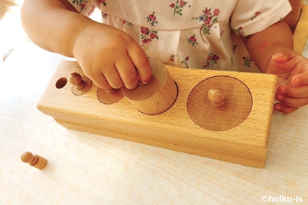 モンテッソーリ教具の円柱さしで遊ぶ子どもの手