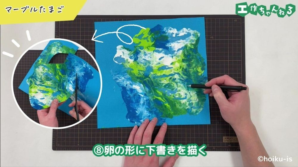 画用紙をたまごの形に切っている手元