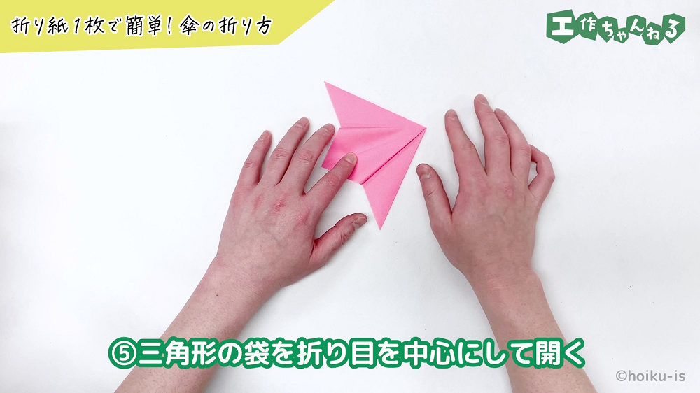 折り紙を中心の折り目に合わせて折っている手元