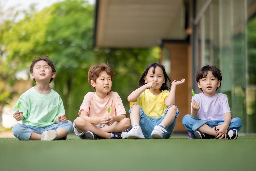 屋外で並んで座っている子どもたち