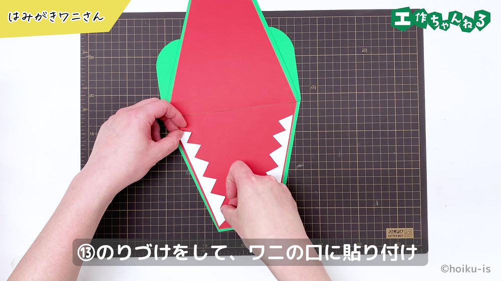 ギザギザに切った画用紙をワニの口に貼り付けている手元
