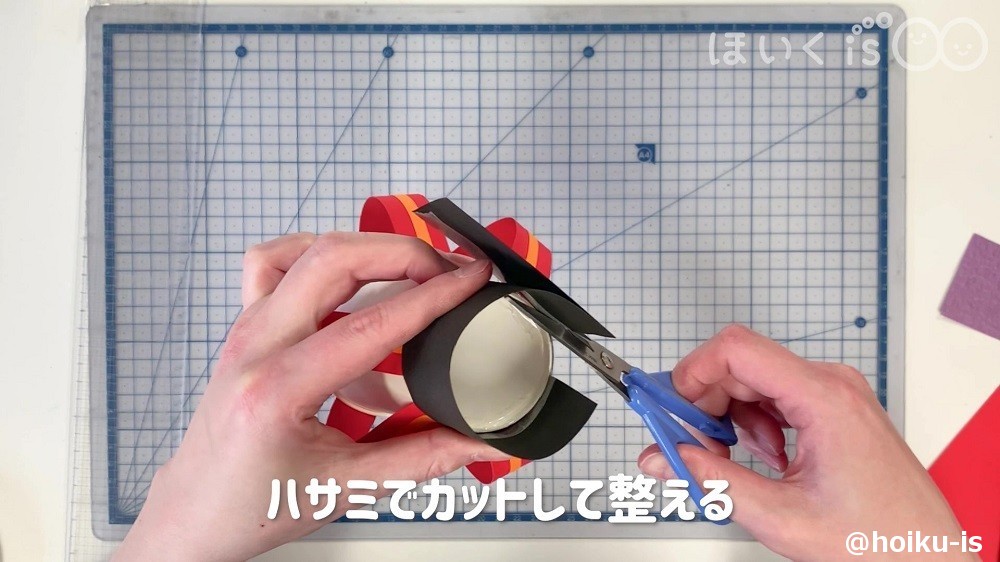 黒の色画用紙をハサミでカットして整えているところ